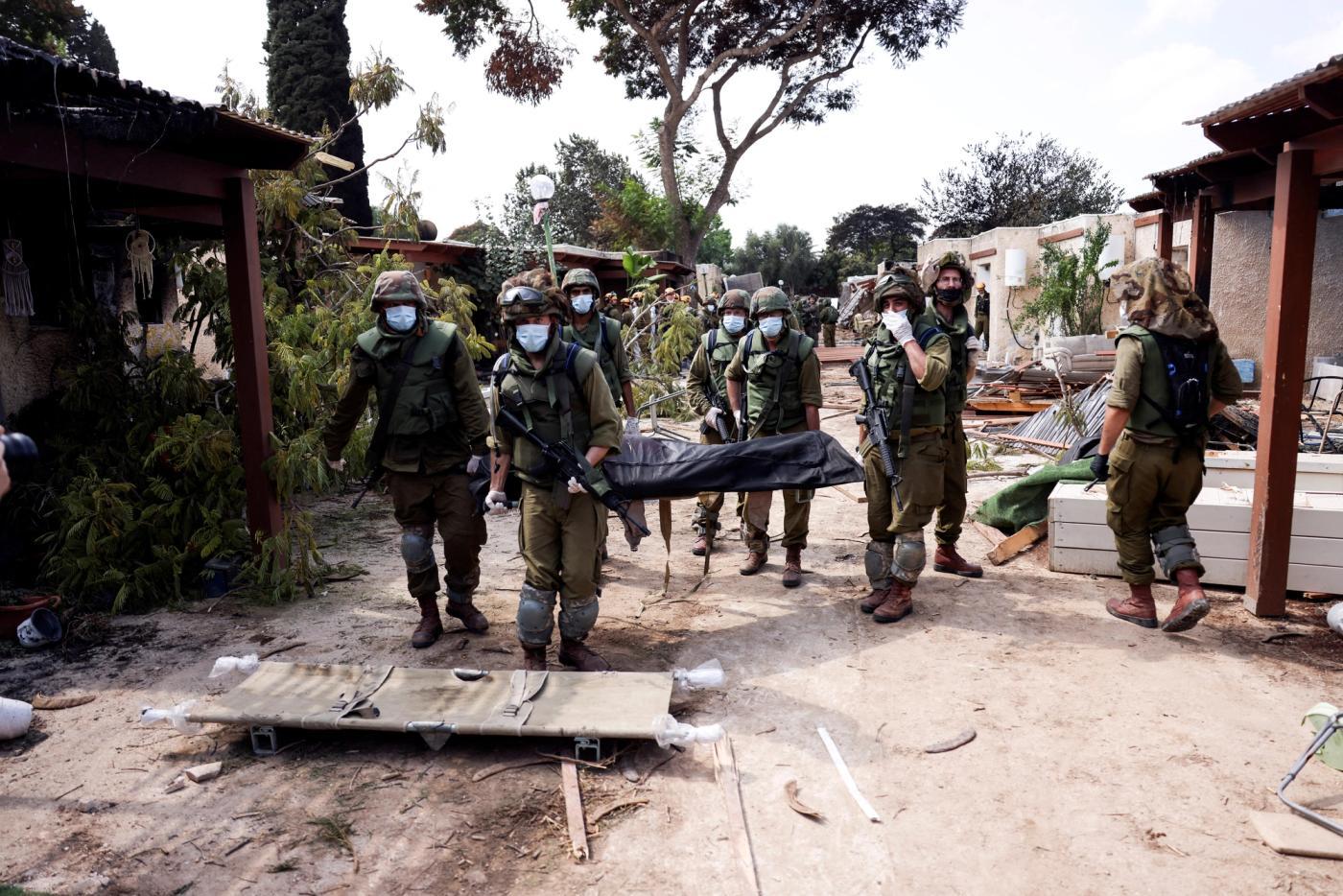 Israeli Soldiers Carry Out Body of Dead Person in Kibbutz Kfar Aza: Unconfirmed Reports of Dozens of Dead Babies and Children