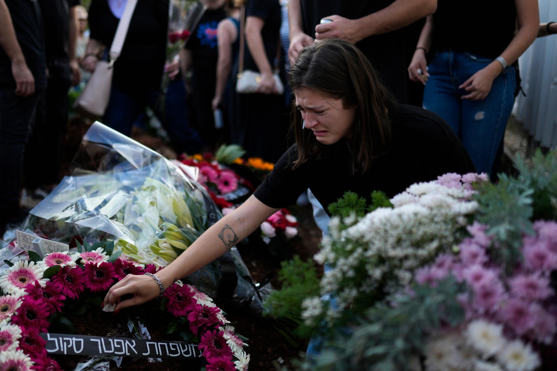 In lutto: le persone in lutto piangono sulla tomba di una donna israeliana uccisa sabato nel massiccio attacco terroristico compiuto da Hamas.