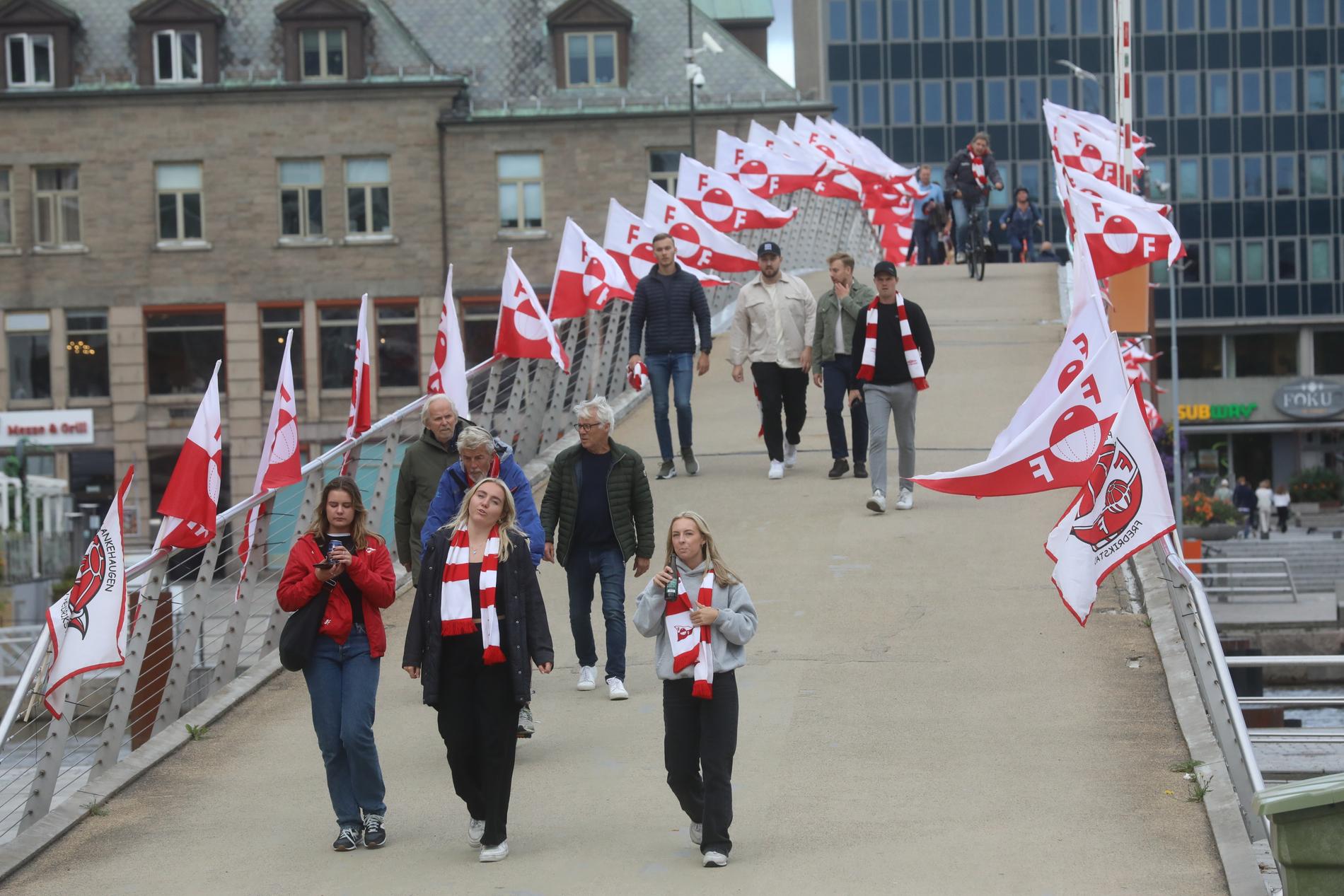 La gente attraversa la passerella dal centro e si dirige verso lo stadio Fredrikstad per guardare una partita dell'FFK.