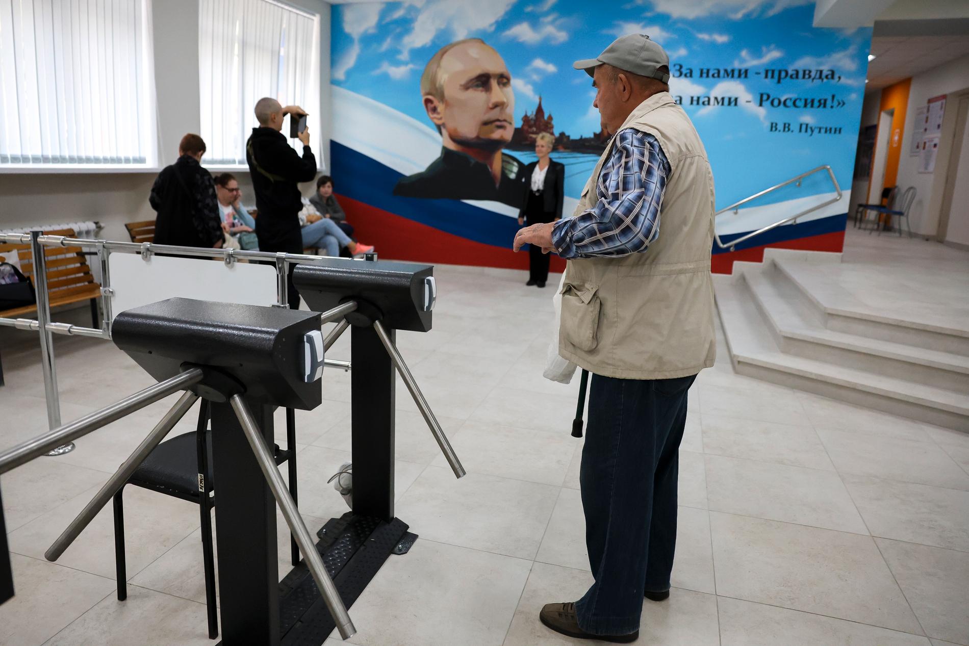 Polling station: A man at a polling station in Russian-controlled Donetsk.  Behind him is a large poster with a picture of Vladimir Putin and a quote from the president.